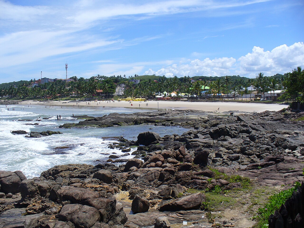 Praia de Batuba em Ilhéus com mar, faixa de areia e trecho rochoso, contexto de orientação de segurança para turistas em inglês